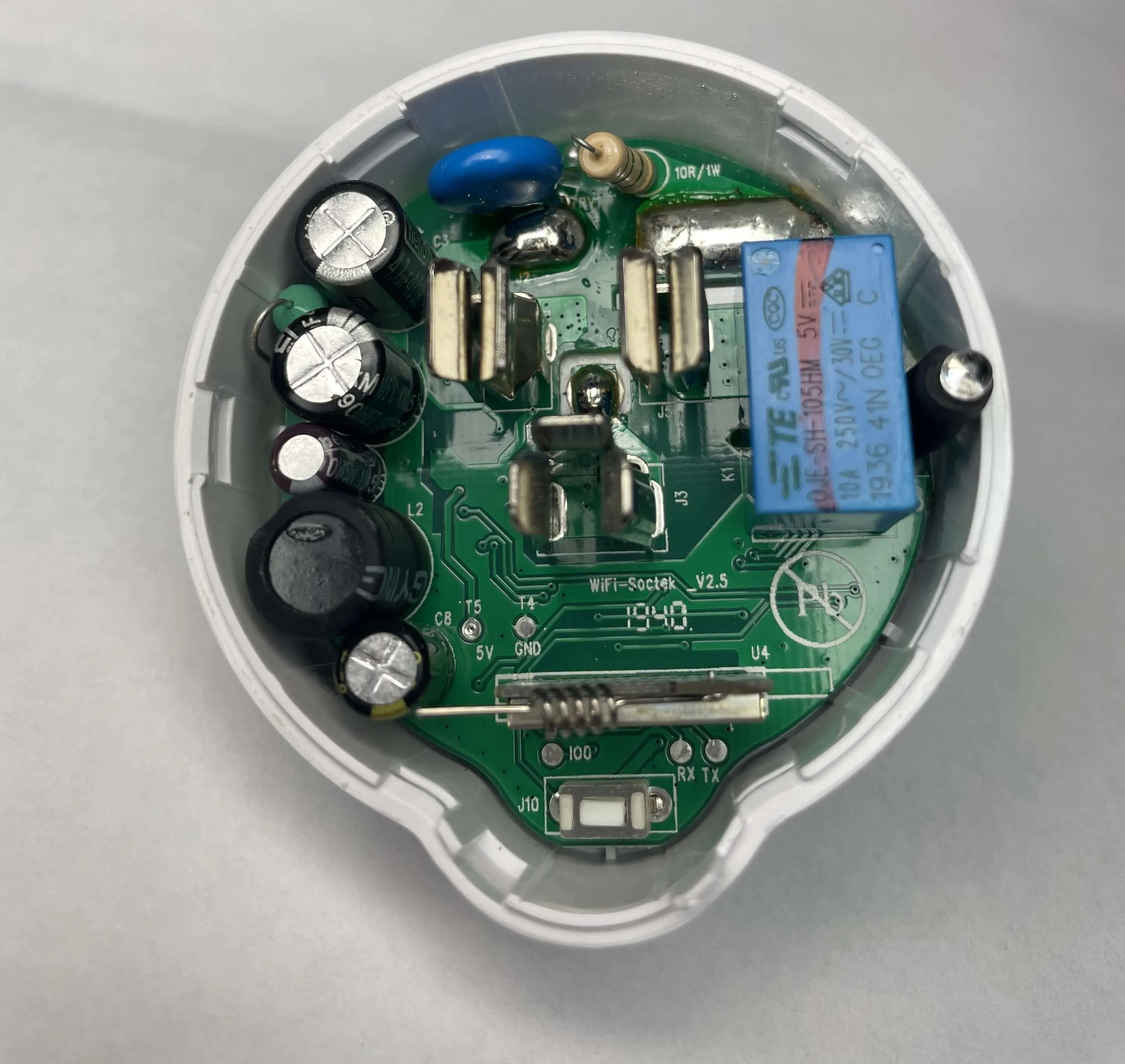 Etekcity Voltson ESW01-USA-R6P PCB A top-down view of the Etekcity Voltson ESW01-USA-R6P's PCB. At the bottom of the PCB, there is an AI-Thinker ESP 01E module identifiable by its spring antenna. Below the ESP module, there are three test pads labeled, from left to right, as IO0, RX, and TX. Above and to the left of the ESP module, there are two test pads labeled, from left to right, as T5/5V and T4/GND.